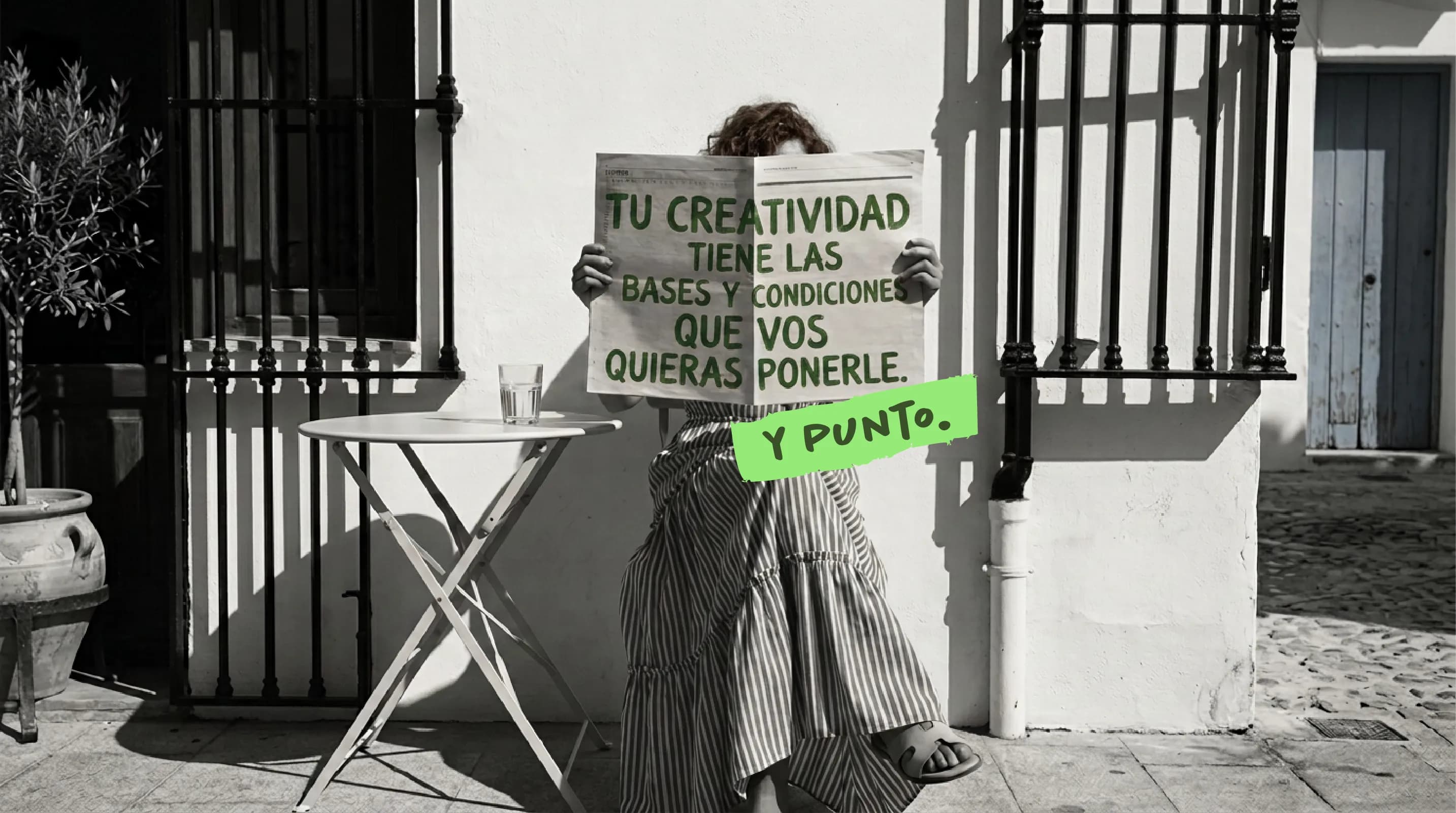 Lilen de pie en una calle, sosteniendo frente a su cara un cartel escrito a mano que dice: tu creatividad tiene las bases y condiciones que vos quieras ponerle. Y punto.